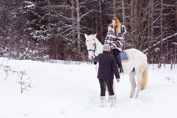 Fototapeta na wymiar Girl, horse trainer and white horse in a winter