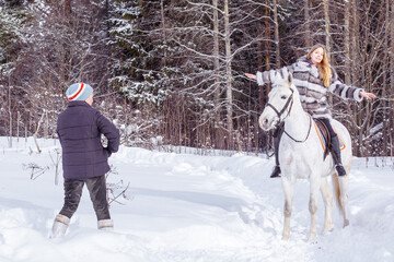 Girl, horse trainer and white horse in a winter