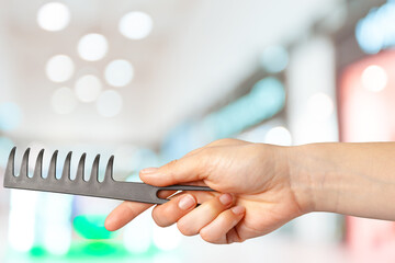 Female hand holding barber comb in cosmetic store