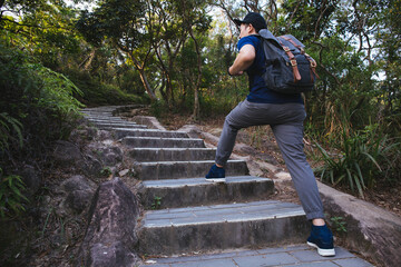 Man hiking in the forest as he climbs on the stair - travel and hiking