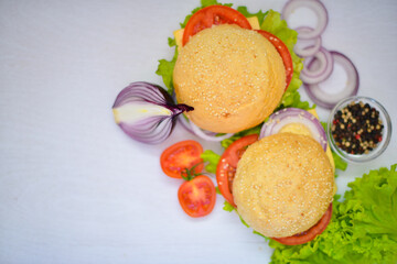 Hamburger with cheese, meat, tomatoes and onions and herbs. On Wooden background. Top view. Free space.