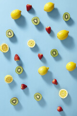 Strawberries, lemons and kiwi fruit on blue background, top view