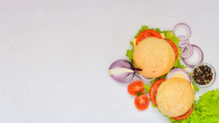Hamburger with cheese, meat, tomatoes and onions and herbs. On Wooden background. Top view. Free space.