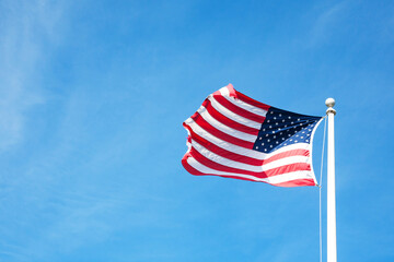Fototapeta premium American flag with blue sky and sunlight for Memorial Day or 4th of July.
