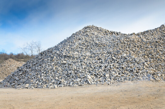 Pile of gray gravel stones  with blue sky and clouds background