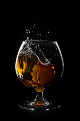 brandy or whiskey pouring into glass on a black background