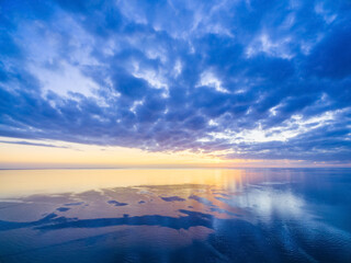Naklejka na ściany i meble Sunset over ocean - blue cloudy sky, sun, and smooth water