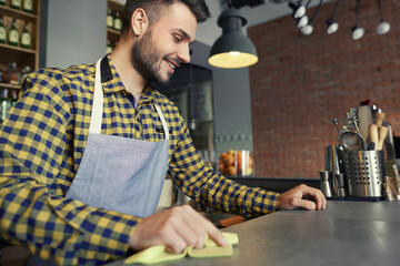 Waiter cleaning bar counter before work