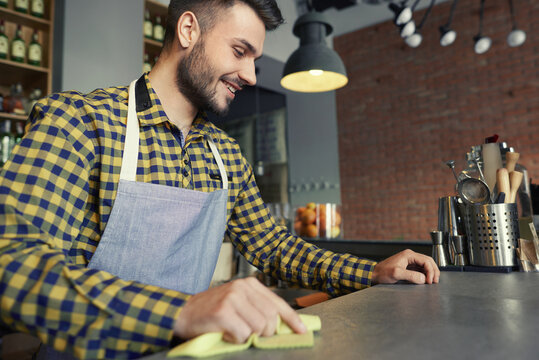 Waiter cleaning bar counter before work