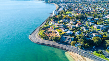 Aerial view on a road running along sea shore with residential suburbs on the background. Auckland, New Zealand.