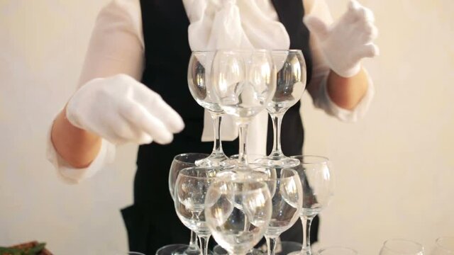 waiter puts the glasses for champagne on the table