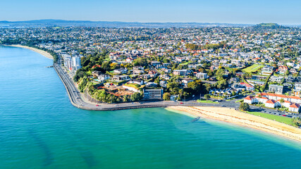 Aerial view on a road running along sea shore with residential suburbs on the background. Auckland,...