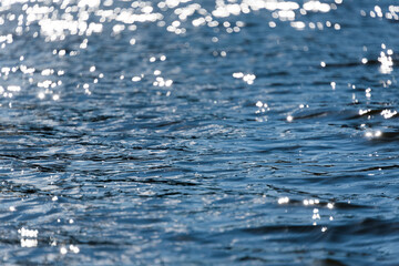 Water bokeh background. Defocused water surface with waves glittering in the sun