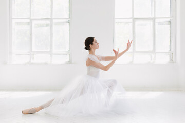 Fototapeta na wymiar Young and incredibly beautiful ballerina is posing and dancing in a white studio