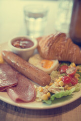 English breakfast with fried eggs, bacon, sausages, beans, toasts and fresh salad