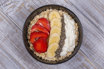 Muesli made from red strawberries, banana, chia seeds, oat flakes, honey and dressed with yogurt