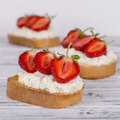 Sandwich of strawberry and cottage cheese on the wooden table, close up