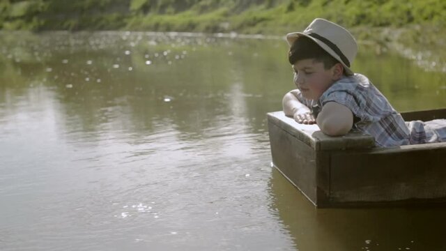 Boy sends sailing ship from the newspaper while sitting in a boat