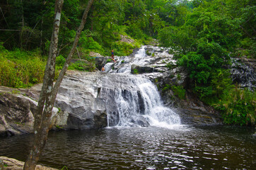 Fototapeta premium KHLONG LAN, THAILAND - August, 2016: Jungle landscape with flowing water of Khlong Nam Lai waterfall in Kamphaeng Phet province at deep tropical rain forest. Khlong Lan National Park, Thailand