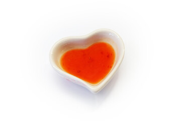 Obraz na płótnie Canvas Sweet and spicy chicken sauce in small heart shape bowl on white background