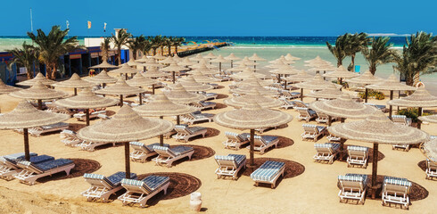 Chaise lounge and parasols on the beach against the blue sky and sea. Egypt, Hurghada