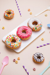 Party. Different colourful sugary round glazed donuts and bottles of drinks on light color background.