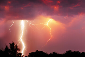 Fork lightning over dark orange sky on stormy day