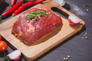 Raw beef on a cutting board  with spices and ingredients for cooking.