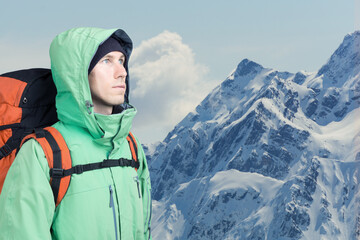 Man alpinist looks up against a winter mountain landscape.