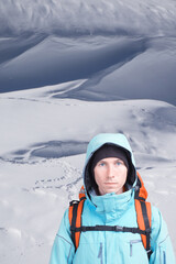 Young man traveler standing on snowy field with footprints in the snow.