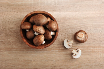 Fresh brown chestnut mushrooms whole in wooden plate
