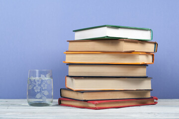 Book stacking. Open book, hardback books on wooden table and blue background. Back to school. Copy space for text.