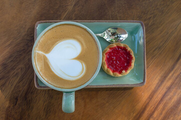 coffee cup with heart shape with strawberry biscuit on blue plate