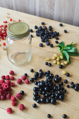 Red, white, black currant, red and black raspberries, white strawberries and mint leaves with glass jar on wooden table as ingredient to healthy cocktail, beverage, yogurt, smoothie