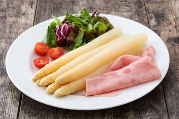 White asparagus with salad and ham on wooden background

