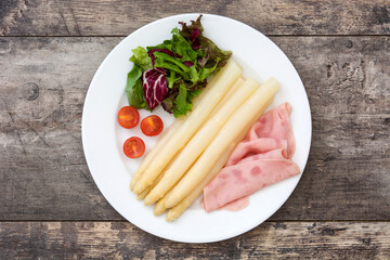 White asparagus with salad and ham on wooden background

