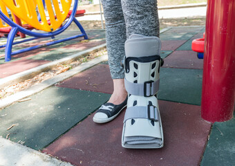 Broken leg the splint for treatment of injured woman wearing sportwear on playground background