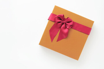 Top view of yellow gift box with red ribbon on white background, holiday and event concept