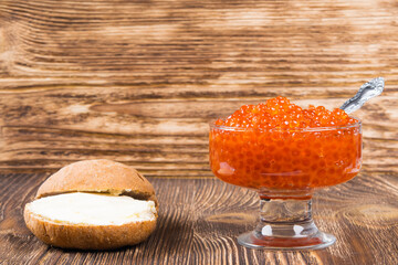 Old wooden background with a plate of red caviar, place for inscription