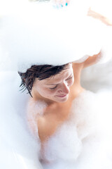 Relaxed sexy young naked woman in bath with foam on her head, luxury villa, tropical Bali island, Indonesia.