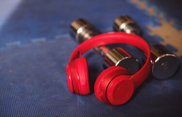 Obraz na płótnie Canvas Red headphone and dumbbell on blue ground in gym. fitness concept music relax for fitness