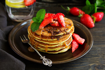 Pancakes with caramel and strawberries for breakfast.