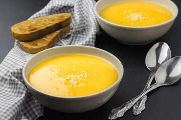  Healthy pumpkin soup and whole grain bread on a dark background. 