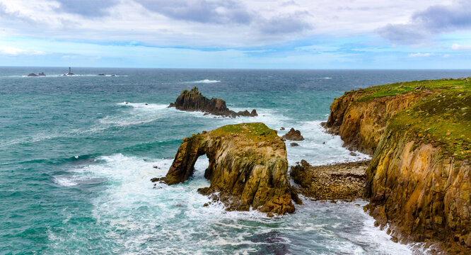 Enys Dodman, a rock arch about 1km south of Lands End, The Armed Knight and the Longships Reef can be seen beyond.