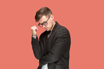 Young handsome man in black suit and glasses isolated on red background