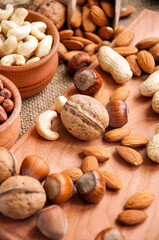 Almonds, cashew, walnuts and hazelnuts in wooden bowls on wooden and burlap, sack background