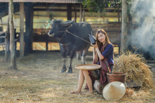 Thailand beautiful country woman listening radio with farm and buffalo background
