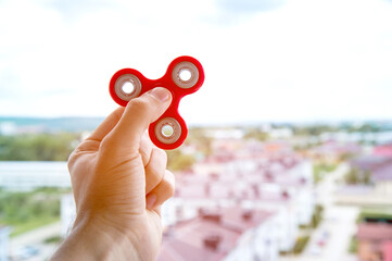 The hand plays with a spinner against the background of the urban landscape in the city fidgeting...