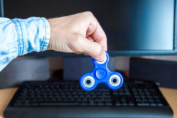 Man's hand holds a spinner on the background of a personal computer close-up