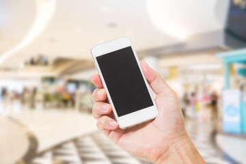 Hands holding mobile phone with blurred image of shopping mall